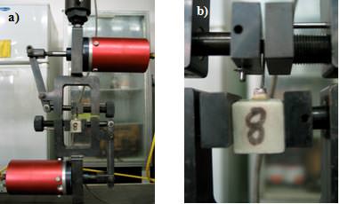 Figura 2 a) Mordazas neumáticas de la máquina Instrom. b) Espécimen con Perno-Muñón Colado colocadas en la máquina de pruebas universales.